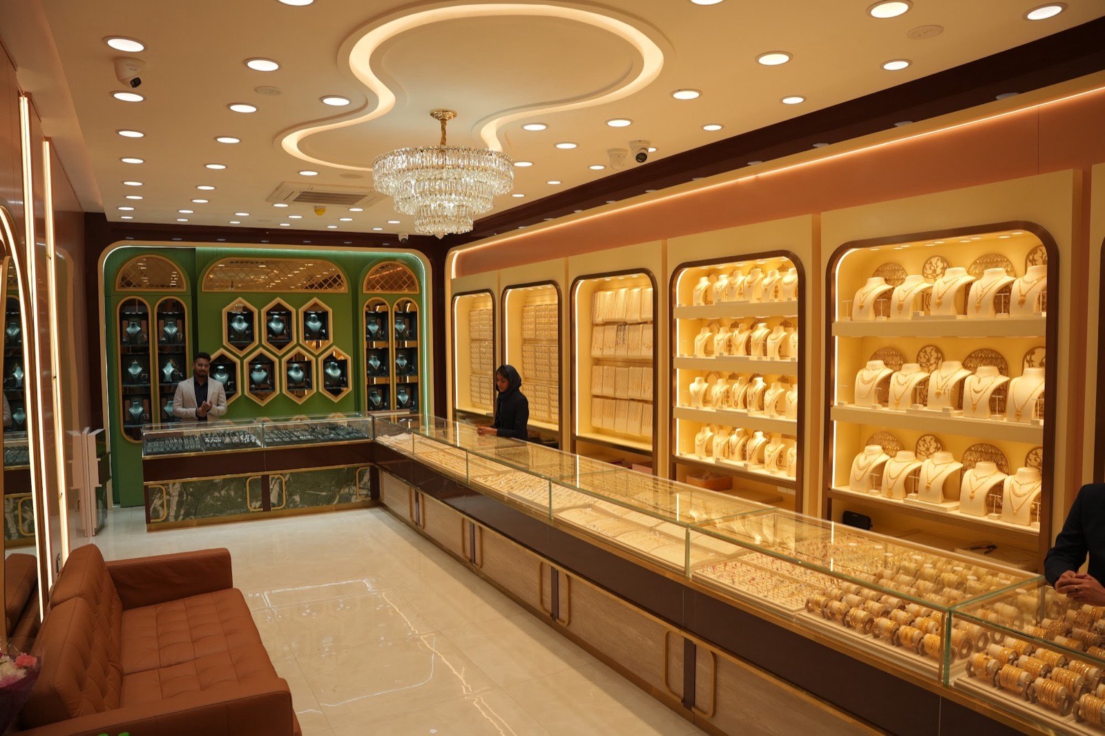 Inside The Grand Gold and Diamonds showroom, with lit display cases of gold necklaces and a crystal chandelier